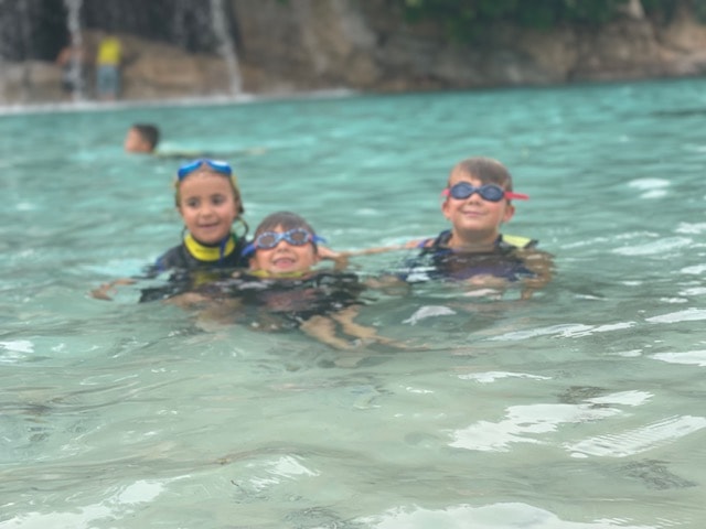 Smiling family posing with a dolphin, capturing a once-in-a-lifetime memory. Discovery Cove Orlando. Things to do Discovery Cove. Discovery Cove with Kids.