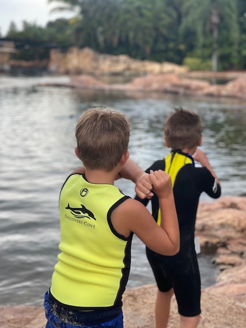 Discovery Cove Orlando: Perfect Guide for 2025 4 Family swimming with a dolphin in a calm, tropical lagoon at Discovery Cove Orlando.