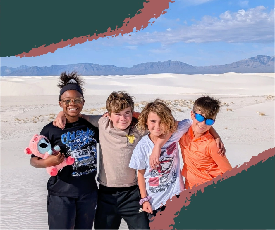 Children running and playing on a white sand dune at White Sands National Park under a clear blue sky.